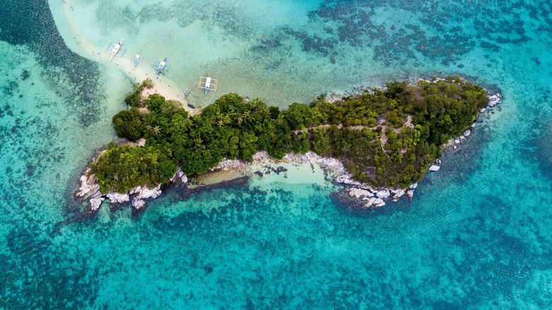 Small boats are near the beaches of Ilha da Queimada Grande