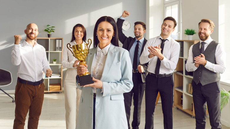 Person winning award in the workplace, surrounded by others