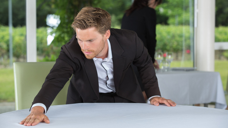 Man in suit smoothing out table cloth