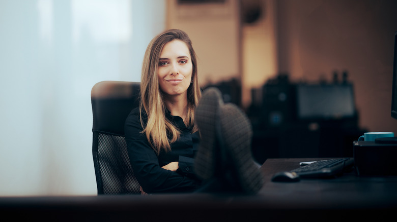 Woman smirking with feet up on desk