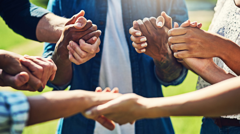 People stand in a circle holding hands