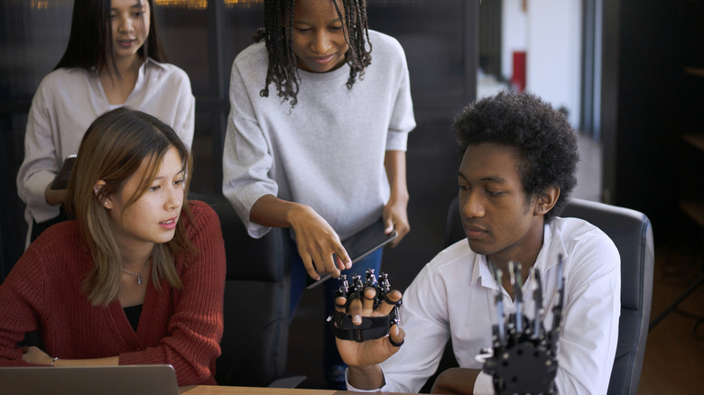 Four students working on a mechanical hand tech project in a classroom