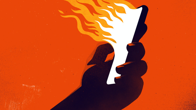 A graphic of a hand holding a phone with flames emerging from it against a bright orange background