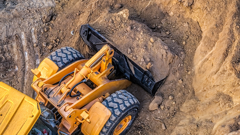 A yellow bulldozer excavates a dirt mound