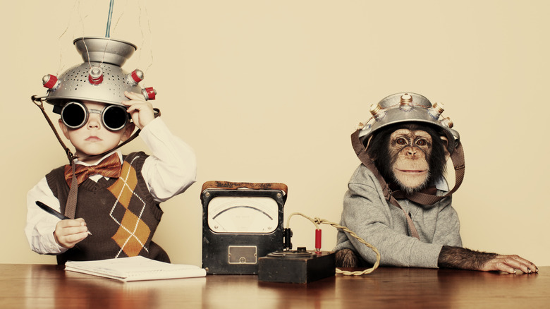 boy and chimp at a desk wearing collanders with scientific equipment