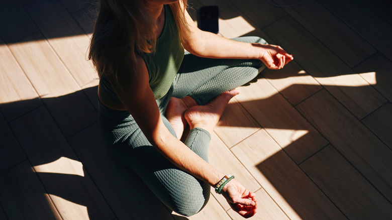 A woman sits on a floor meditating