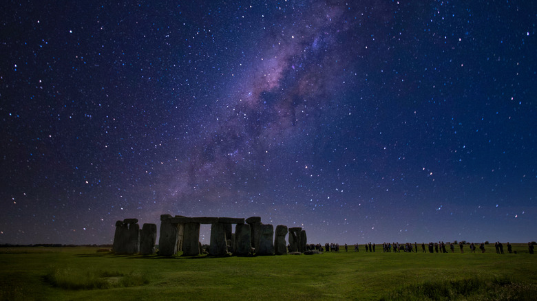 Visitors at Stonehenge at night under a starry sky