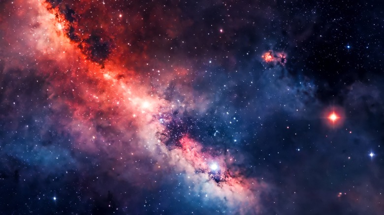 A vivid image of space showing a multitude of stars amid a blue and red gas cloud