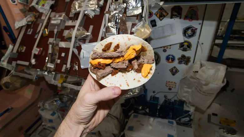 A tortilla covered in beef, cheese, tomato paste, and mustard