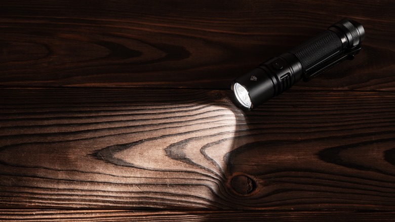 Lit flashlight on wooden table