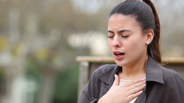 Woman struggling to breathe on a park bench