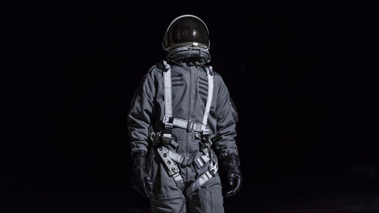 Lone astronaut standing against pitch black space