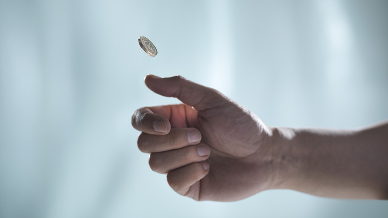 Hand flipping a coin against blurred background