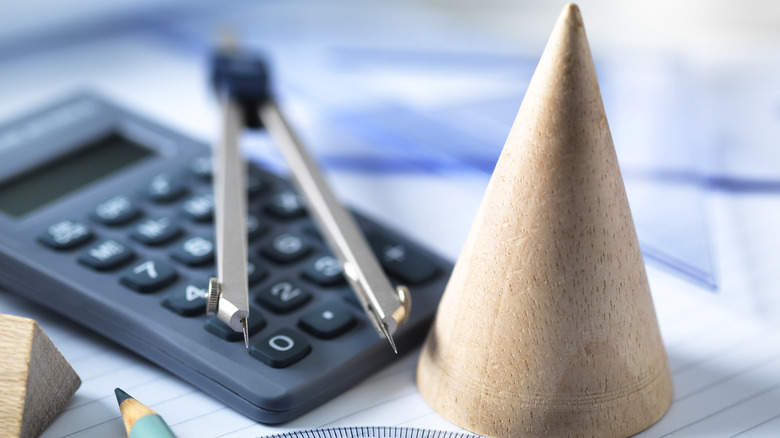 Compass, calculator, and wooden cone on papers