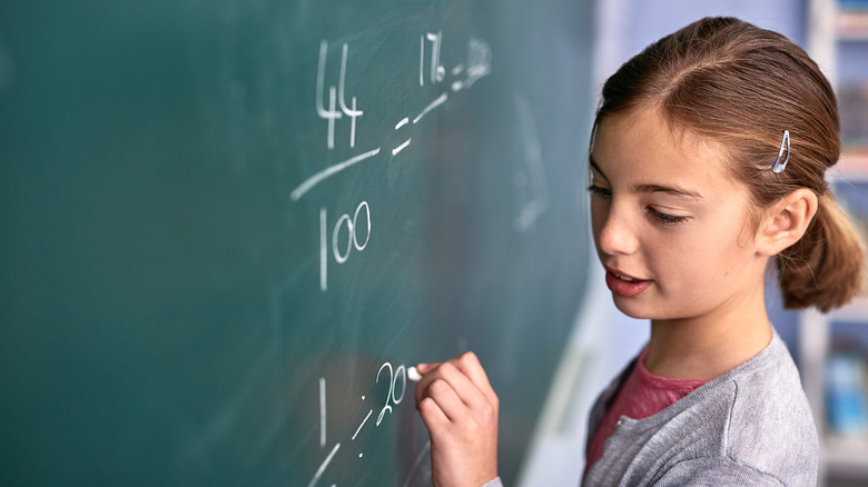 Girl writing fractions on a blackboard