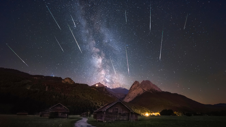 Shooting stars in the night sky above mountain cabins