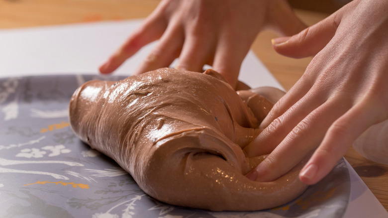 Person kneading chocolate slime with their hands