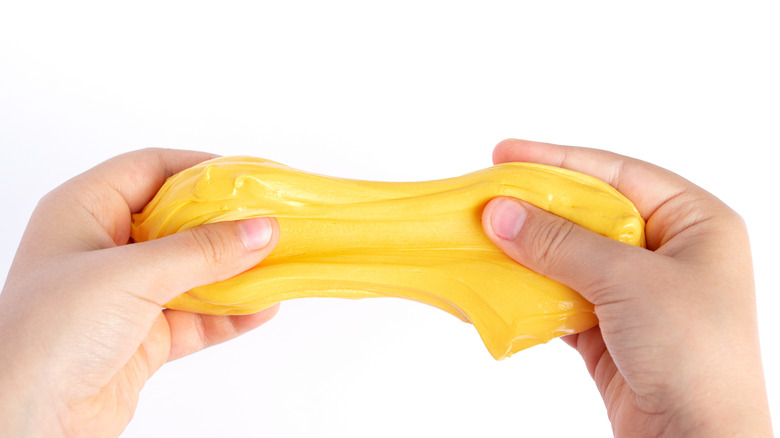 Person stretching yellow slime in their hands