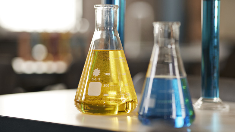 Two flasks filled with yellow and blue liquid on a desk