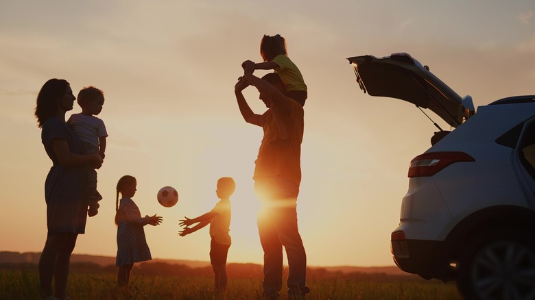 silhouette of family of four playing by car