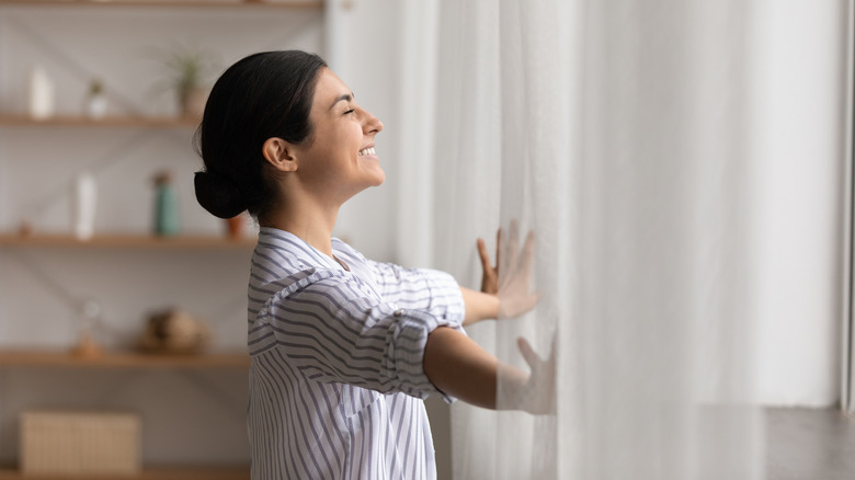 Woman opening curtains and smiling