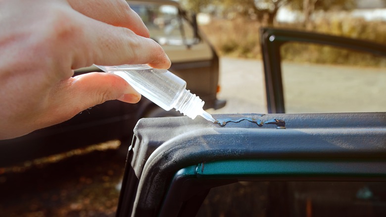 A hand applying silicone adhesive to silicone rubber seal