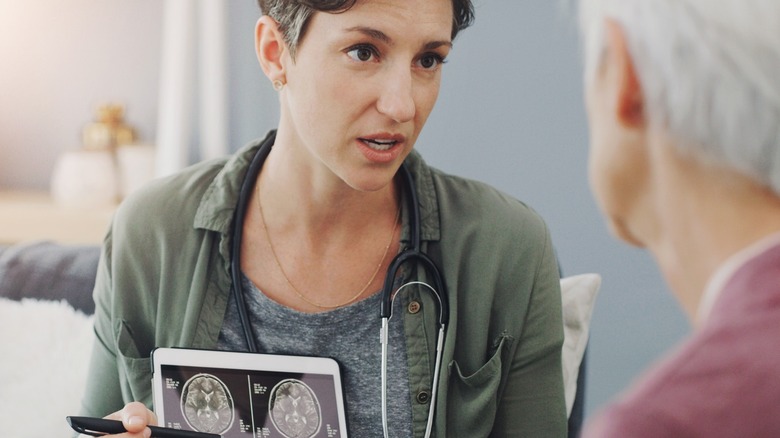 A doctor talks through images of brain scans with a patient in hospital