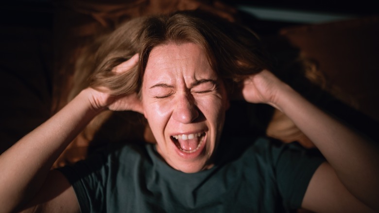 A woman is shown holding her head in distress