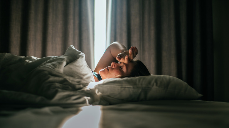 Woman resting in a bed with curtains slightly open