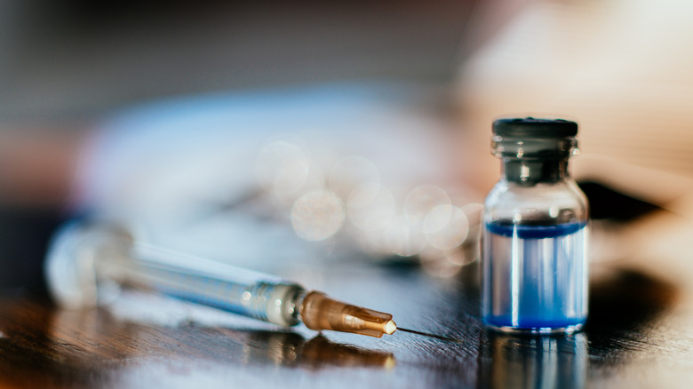 Selective focus of ampule with blue liquid and syringe