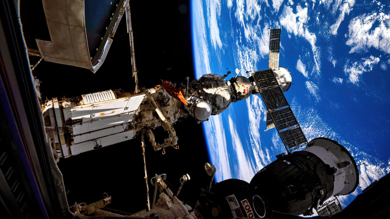 A spacecraft docks at the International Space Station with the curvature of the blue Earth in the distance