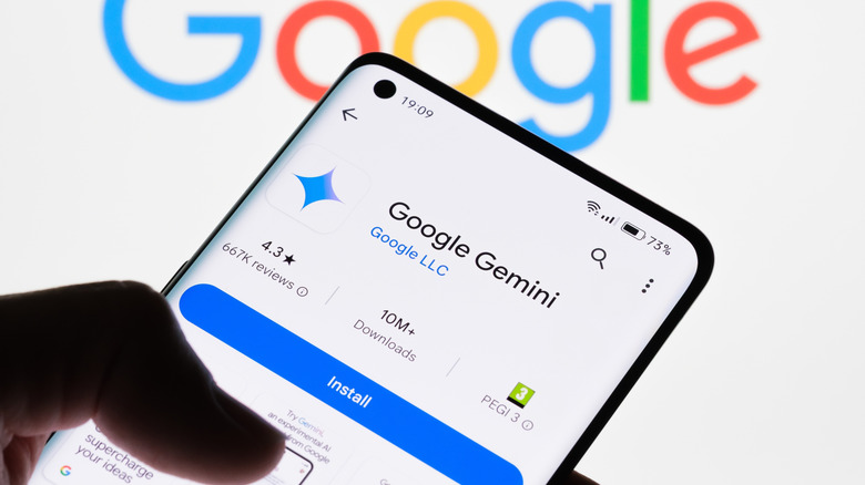 Google Gemini is shown in the Android app store on a phone screen, with a thumb visible in the foreground against a white backrgound with the Google logo on it