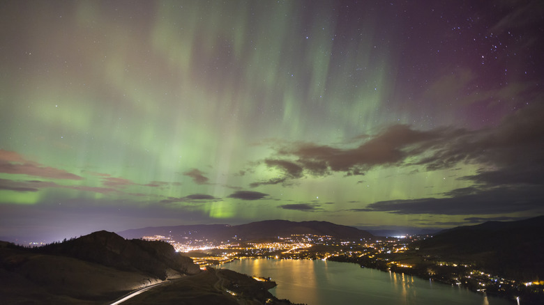 Striated streaks of green light in the night sky above a seaside town