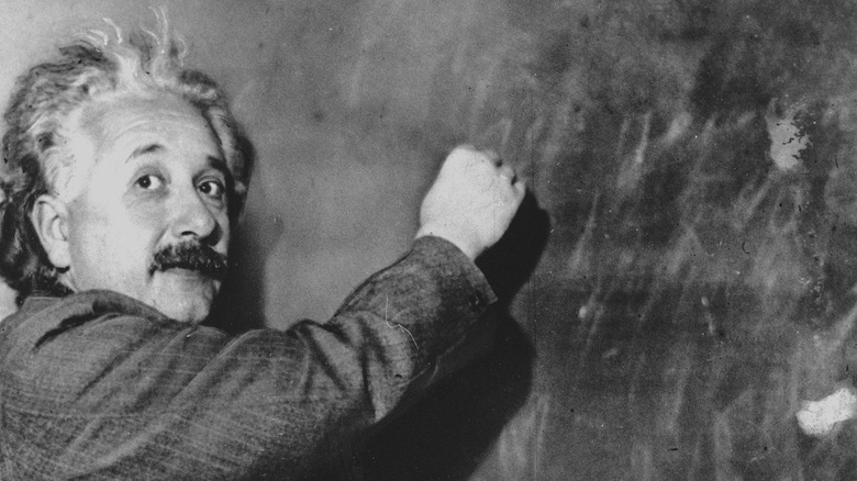 Einstein looking at camera while writing on a blackboard