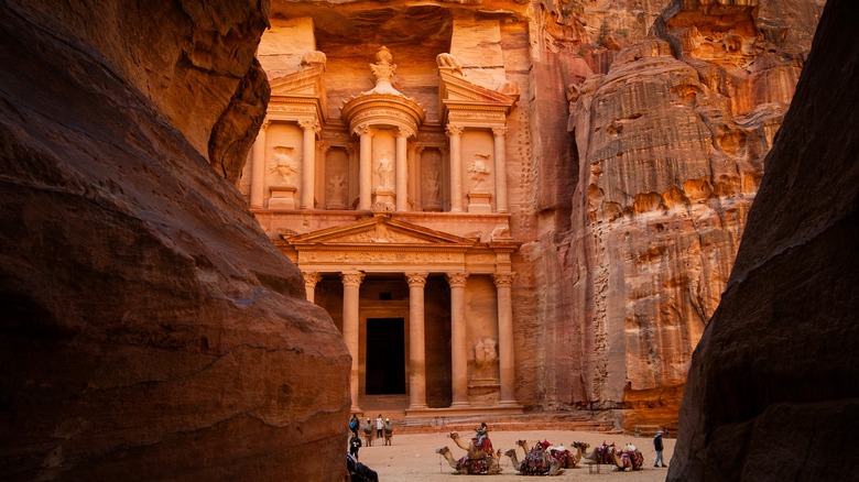 Visitors and camels standing outside of Al-Khazneh