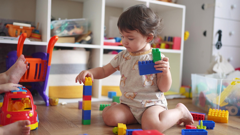 Toddler sitting on the floor and playing with building blocks