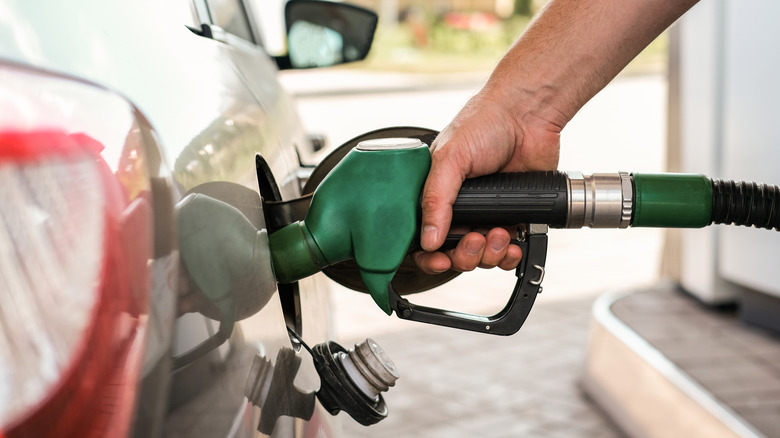 Close-up of hand pumping gas with green nozzle