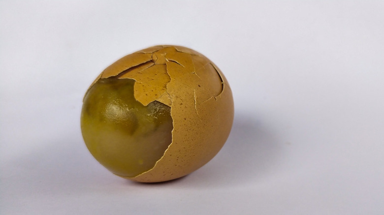 Rotten egg with cracked shell on white background