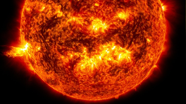 Bright light of a solar flare on the left side of the sun and an eruption of solar material shooting through the sun's atmosphere