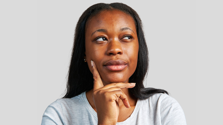 Woman with hand to cheek and thinking deeply