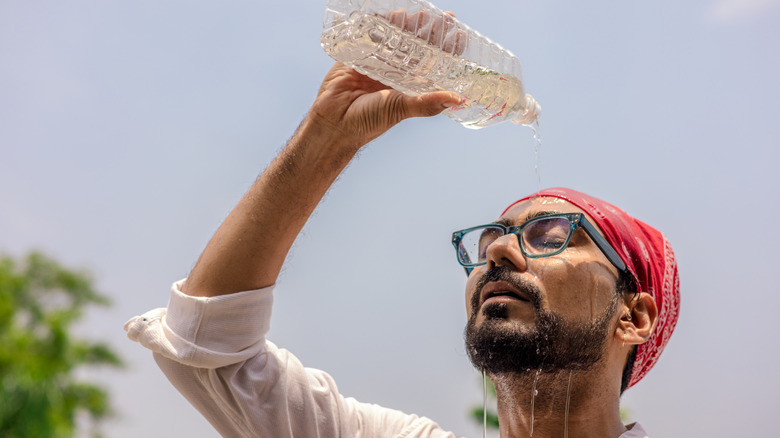 Man pouring a bottle of water on his head