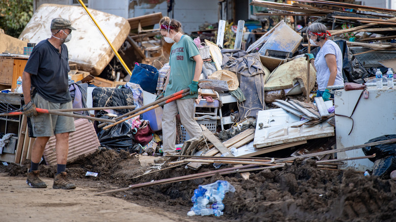 Three people cleaning up debris