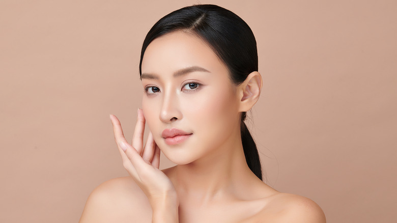 A model poses for the camera against a plain peach background