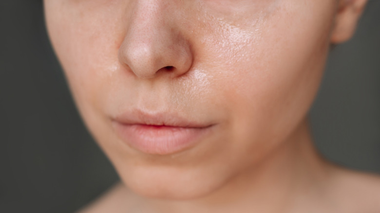 A closeup shows the lower half of a woman's face against a dark background