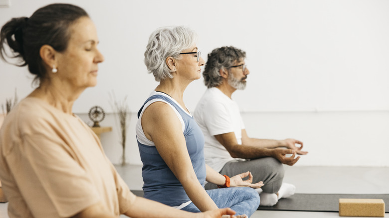 Three adults meditating in a yoga class