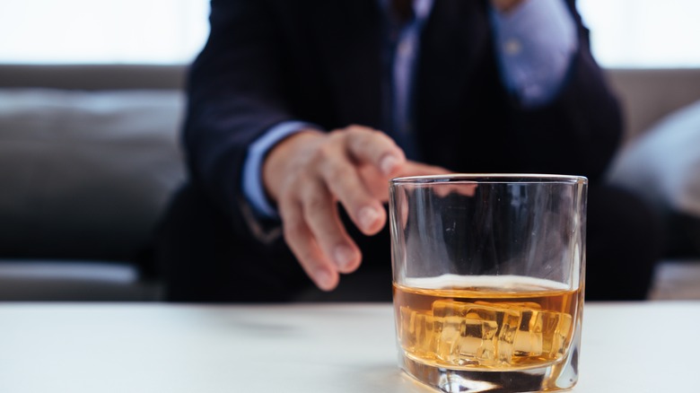 Man in business suit reaching for alcoholic beverage