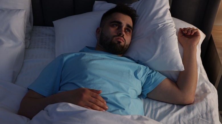 Man laying in bed with insomnia