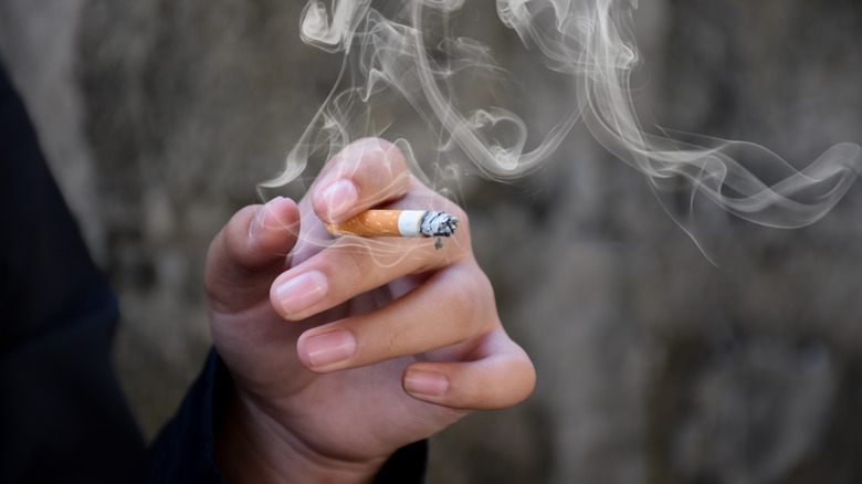 Close-up of a hand holding a lit cigarette