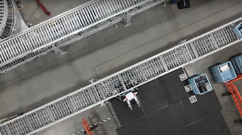 A top down view of Agility Robotics' Digit robot standing at a conveyor belt while working in a factory