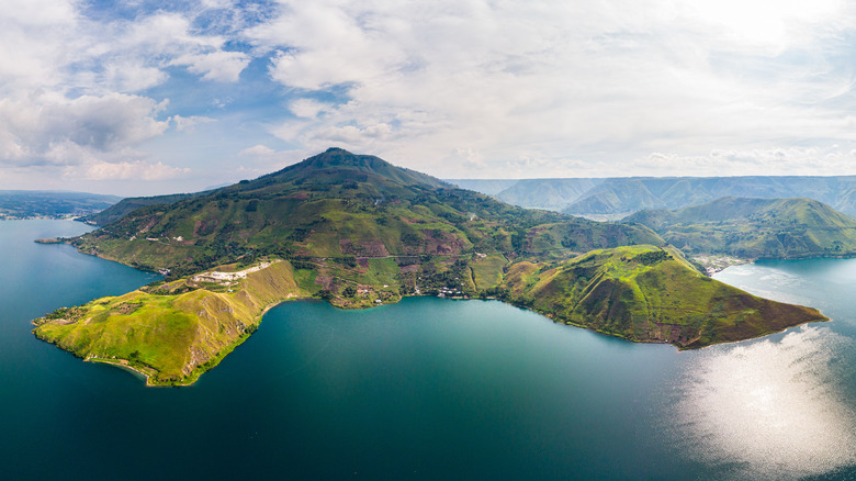 A aerial view of a lake ringed by green hills and valleys